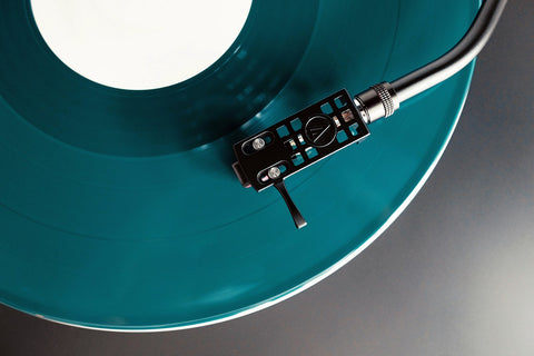 Teal-colored vinyl record playing on a turntable
